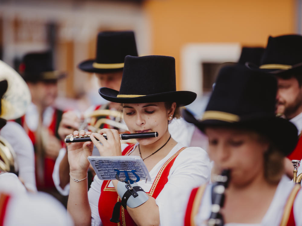 Flötenspielerin und Orchester beim Stadtfest in Mittersill, festliche Atmosphäre vor der Kulisse der Stadt.