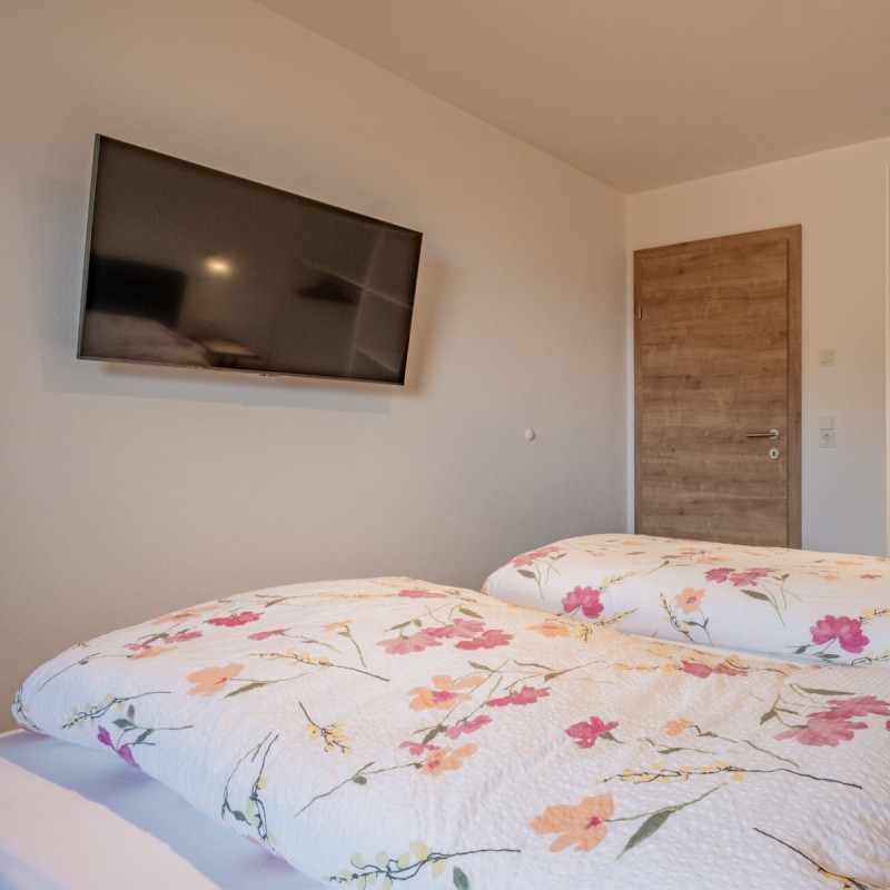 Schlafzimmer der Ferienwohnung Hoferlitzlhubgut in Mittersill mit Doppelbett und großem TV, ideal für entspannte Abende