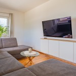 Gemütliche Sitzecke vor einem TV in der hellen Ferienwohnung Hoferlitzlhubgut in Mittersill, ideal zum Entspannen nach einem Tag in den Bergen. thumbnail
