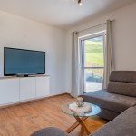 Sitzecke mit Glastisch und Großbildfernseher im stilvoll-modern eingerichteten Ferienhaus Hoferlitzlhubgut in Mittersill. thumbnail