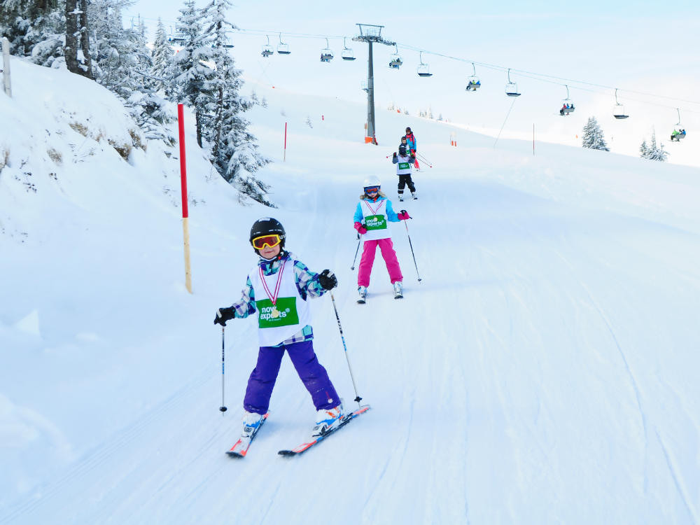 Lachend und mit viel Freude und Spaß im Schnee fährt die Anfängergruppe des Kinderskikurses die Piste am Resterkogel hinunter.