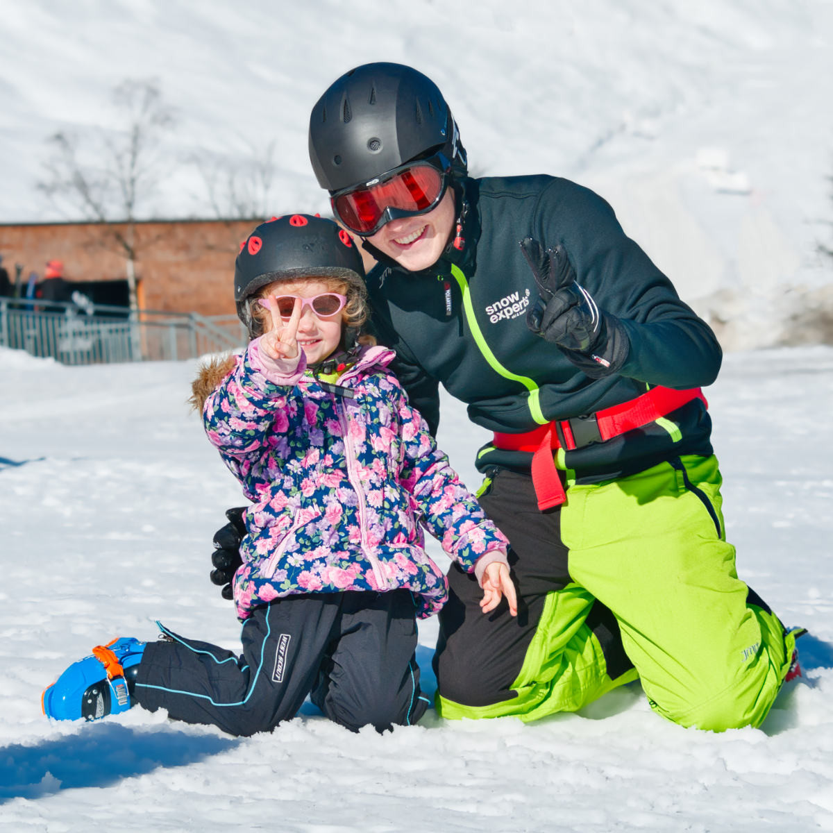 Im Skigebiet KitzSki lachen Skilehrer und Skischüler gemeinsam im Schnee und zeigen die Freude und den liebevollen Umgang mit Kindern.