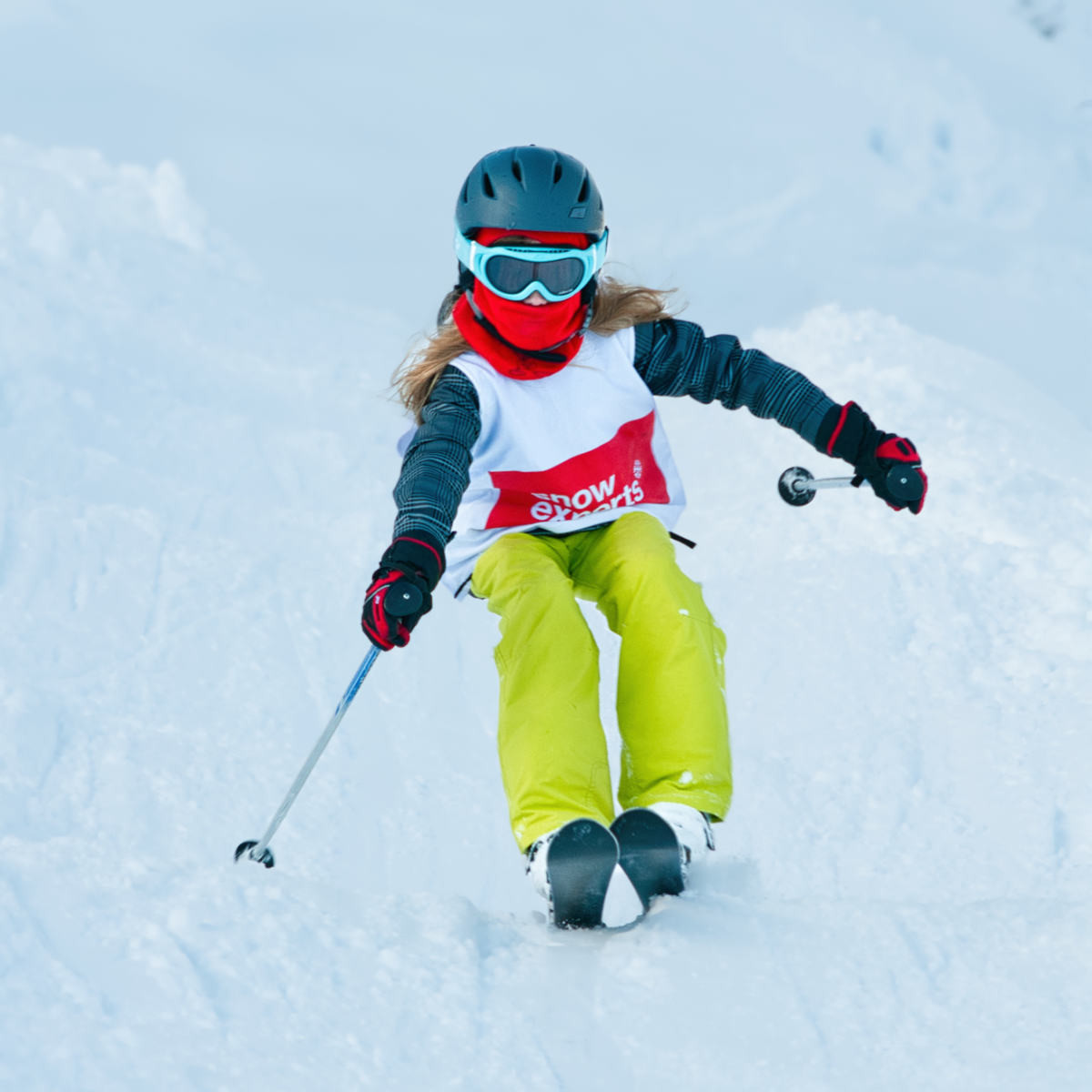 Erfahrene Skischülerin von Snow Experts beim dynamischen Tiefschneefahren abseits der Piste, eindrucksvolle Aufnahme im Skigebiet KitzSki.